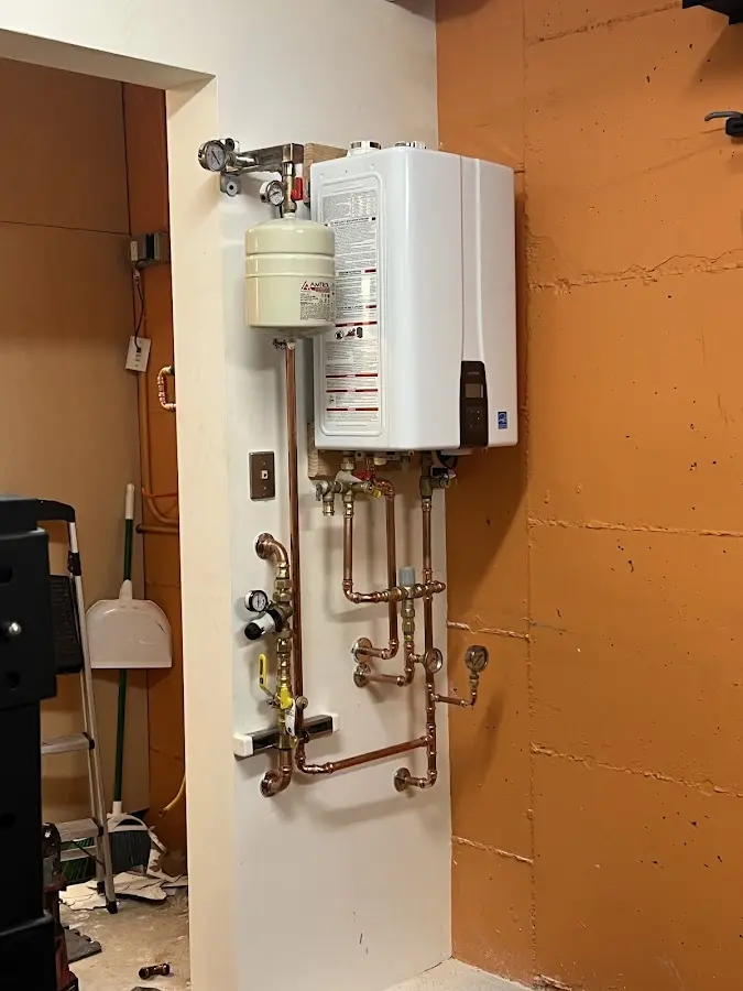 Plumbing technician inspecting water heater connections in Filer